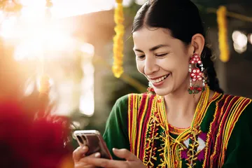 A cheerful woman in traditional clothing using her smartphone during a festive moment, showing how easily the CK6667 app fits into everyday life.